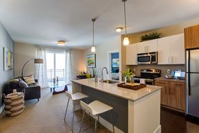 Medford apartment for rent - A kitchen with a white countertop and a dining table with chairs.