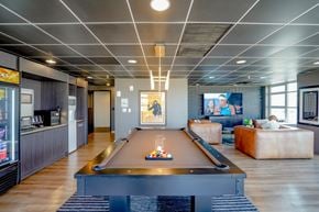 Milwaukee apartment for rent - A pool table is in the middle of a room with a bar and a couch.