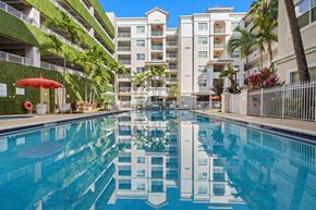 Boyton Beach apartment for rent - A swimming pool in front of a building with a white fence.