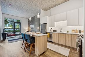 Chicago apartment for rent - a kitchen with white cabinets and a bar and a living room