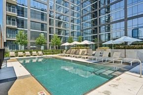 Chicago apartment for rent - an outdoor pool with lounge chairs and umbrellas next to a tall building