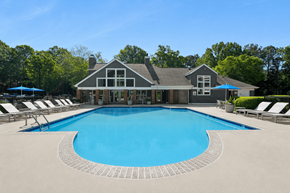 Cary apartment for rent - A large swimming pool in front of a house with a blue sky in the background.