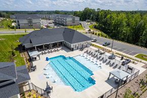 Charlotte apartment for rent - A large swimming pool with lounge chairs and a pavilion is surrounded by a parking lot and buildings.