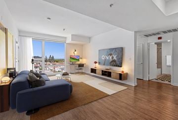 Glendale apartment for rent - A modern living room with a blue sofa and a TV displaying the letters "ONYX".