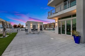 Miami apartment for rent - a patio with chairs and a building with glass doors