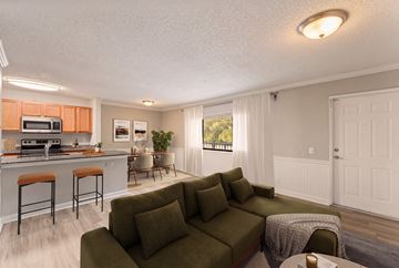 Wellington apartment for rent - A living room with a green couch and a kitchen area with orange cabinets.