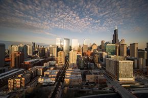 Chicago apartment for rent - A cityscape with a mix of modern and older buildings, a highway, and a partly cloudy sky.