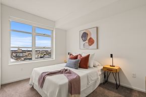 Milwaukee apartment for rent - A bedroom with a large bed and a view of the city through the window.