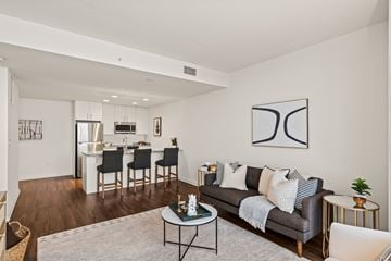 Milwaukee apartment for rent - A modern living room with a grey couch, a coffee table, and a dining table with chairs.