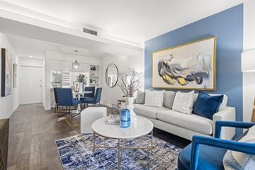 Clearwater apartment for rent - A living room with a white couch, blue chairs, and a painting on the wall.