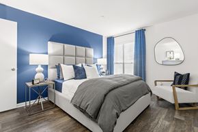 Clearwater apartment for rent - a bedroom with a blue accent wall and a white bed