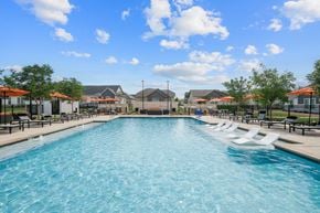 Mckinney apartment for rent - A large swimming pool with lounge chairs and umbrellas.