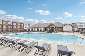 Holly Springs apartment for rent - A pool with sun loungers in front of a building.