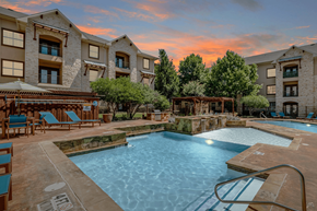 Grand Prairie apartment for rent - A large swimming pool surrounded by lounge chairs and trees.