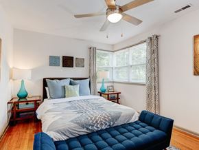 Asheville apartment for rent - A bedroom with a bed, a ceiling fan, and a blue chair.