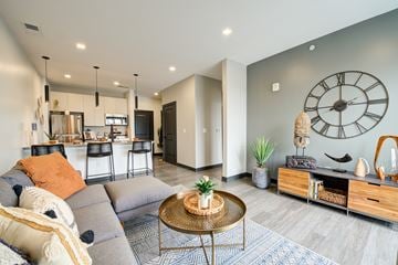 West Lafayette apartment for rent - A living room with a grey couch and a large clock on the wall.