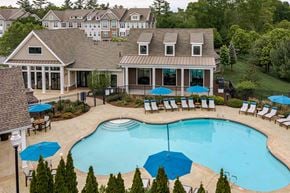 Canton apartment for rent - A large swimming pool surrounded by a deck with chairs and umbrellas.