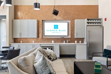 Summerville apartment for rent - A living room with a couch, chairs, and a television displaying the words "Summer Wind".