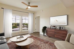 Pensacola apartment for rent - A living room with a couch, a coffee table, a ceiling fan, and a large window with curtains.