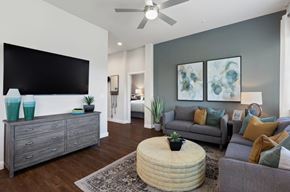Celina apartment for rent - A living room with a grey couch, a round ottoman, and a flat screen TV mounted on the wall.