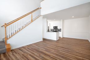 Sharon apartment for rent - View of vacant living room with stairs up to loft and kitchen in background