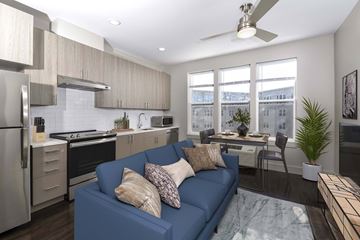 Belleville apartment for rent - A blue couch with pillows is in the middle of a kitchen and living room.