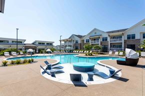 Spring Hill apartment for rent - A large outdoor swimming pool surrounded by lounge chairs and umbrellas.