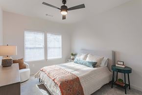 Spring Hill apartment for rent - A bedroom with a bed, a ceiling fan, and a small table with a plant on it.