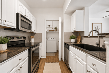 Dallas apartment for rent - A modern kitchen with white cabinets and black countertops.