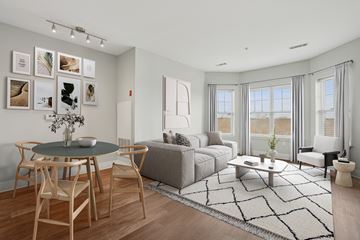 Canton apartment for rent - A living room with a grey couch, a round table with chairs, and pictures on the wall.