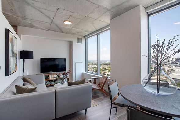 Nashville apartment for rent - A modern living room with a grey couch and a large window overlooking the city.