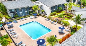 Tamarac apartment for rent - A swimming pool surrounded by lounge chairs and umbrellas.