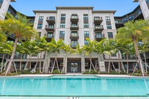 Davie apartment for rent - a large pool in front of a building with palm trees