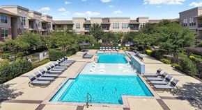Grand Prairie apartment for rent - A large swimming pool surrounded by lounge chairs and trees.