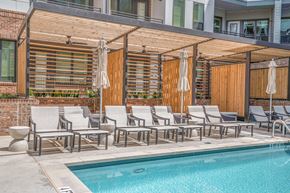 Atlanta apartment for rent - A pool area with chairs and a wooden pergola.