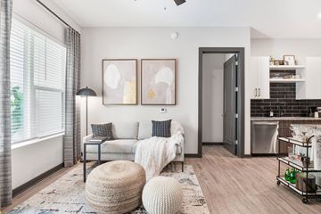 Atlanta apartment for rent - A modern living room with a grey sofa, a white knitted throw, and two abstract paintings on the wall.