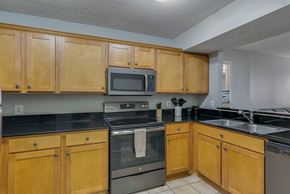 Nashville apartment for rent - A kitchen with wooden cabinets and black countertops.