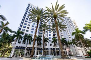 Fort Lauderdale apartment for rent - a tall building with palm trees in front of it and a pool