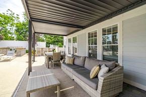 Medford apartment for rent - A patio with a grey couch and a table with chairs.
