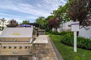 Medford apartment for rent - A stainless steel grill with a yellow sticker on it is on a patio.