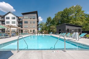 Carmel apartment for rent - North Indianapolis, IN, Apartments Near Monon Trail - North End Apartments - Resort-Style Swimming Pool With Sundeck Lounge Chairs, Pergola, Metal Fence, and Community Buildings.