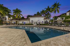 Hollywood apartment for rent - a large swimming pool with lounge chairs and umbrellas in front of a house