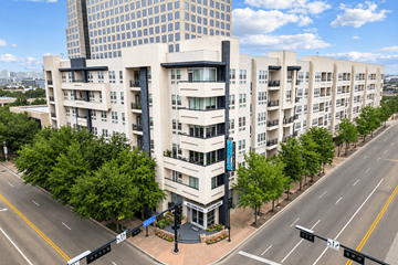 Dallas apartment for rent - A street view of a modern apartment building with a blue sign on the corner.