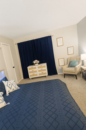 Longview apartment for rent - A bedroom with a bed, chair, and nightstand.