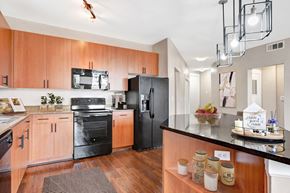 Keller apartment for rent - A modern kitchen with wooden cabinets and black appliances.