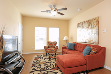 Corpus Christi apartment for rent - A living room with a red couch and a ceiling fan.