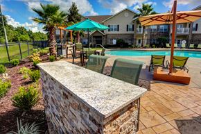 Pensacola apartment for rent - A pool area with a stone wall and a fence.