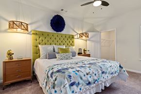 Ashland City apartment for rent - One-Bedroom Apartments in Ashland City, TN - Ashland Farms - Bedroom with Carpeted Flooring, Large Bed, Wooden Nightstands with Drawers, Hanging Lamps, Spacious Closet, and Ceiling Fan.