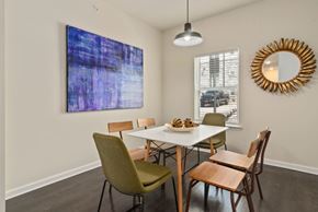Ashland City apartment for rent - Dog-Friendly Apartments in Ashland City, TN - Ashland Farms - Dining Room with Wood-Inspired Plank Flooring, Table and Six Chairs, Mounted Wall Art, Sun-Framed Gold Mirror, Window, and Hanging Light Fixture.