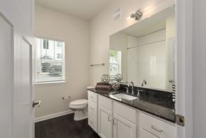 Ashland City apartment for rent - Ashland City, TN Apartments - Ashland Farms - Spacious Bathroom with Wood-Style Flooring, Window, Large Vanity Mirror, Granite Countertop, Sink with Modern Fixtures, and Shower with Tile Backsplash